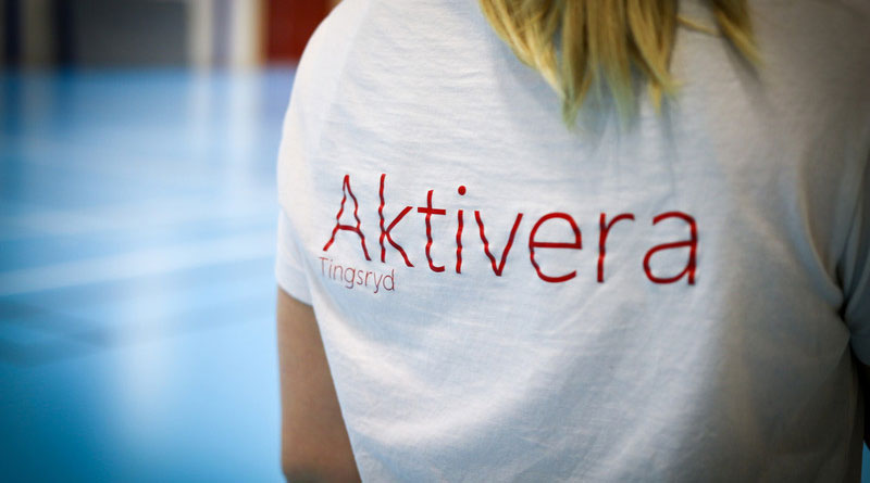 Text på en kvinnas rygg med en t-shirt där det står Aktivera. 