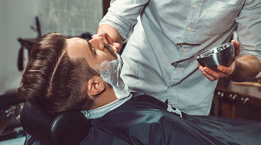 Barberare gör kund redo för rakning