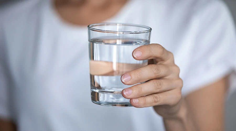 En hand håller i ett glas med vatten