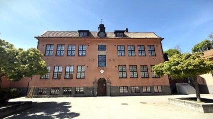 Blå himmel, rosa skolbyggnad och asfalt.