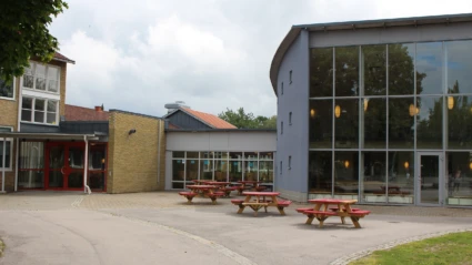 Dackeskolan med asfalterad skolgård med utplacerade bänkar i förgrunden.