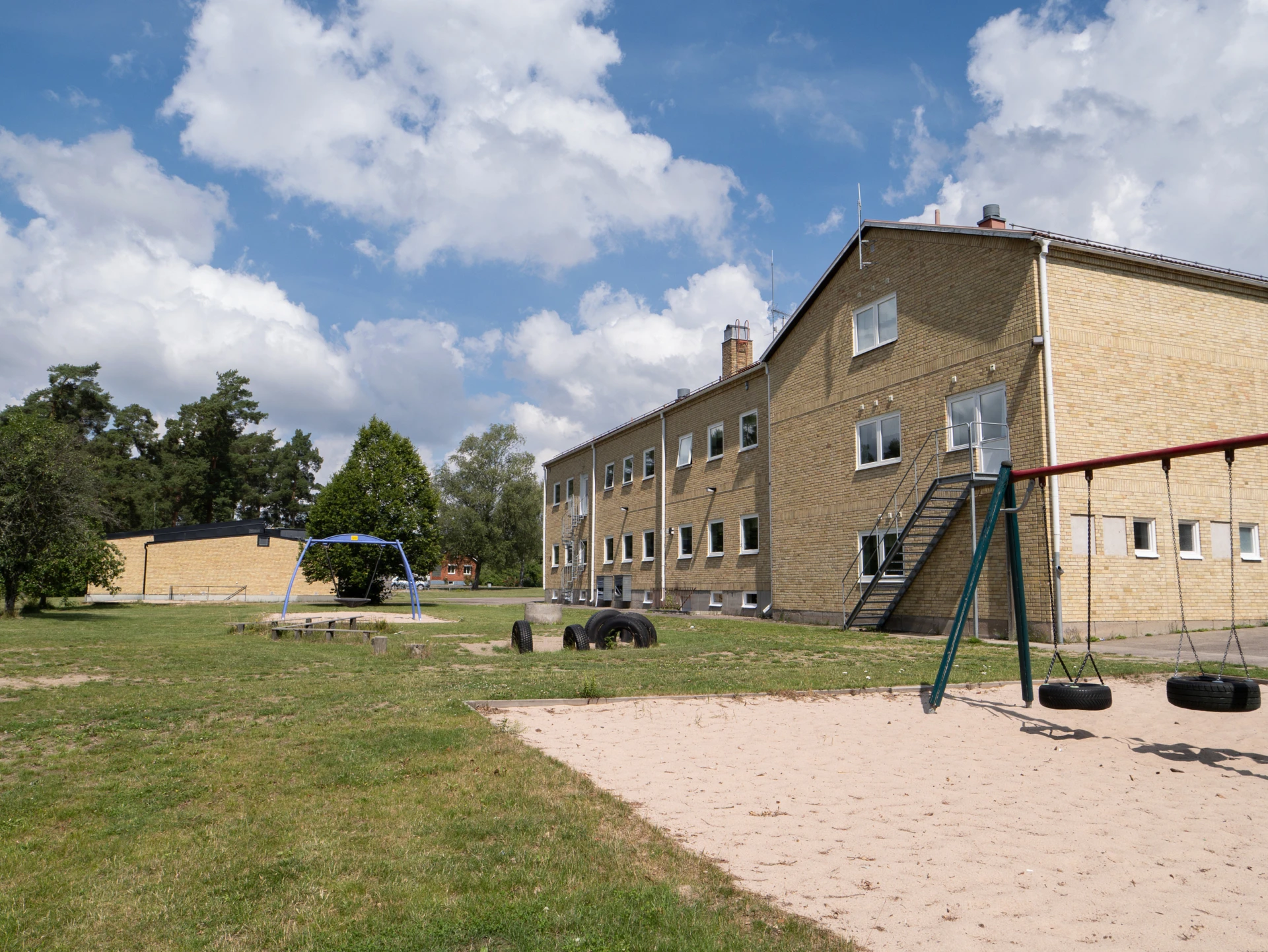 Linnerydskolans gula tegelbyggnad med utegård i förgurnden.