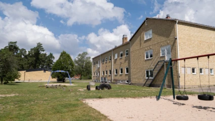 Linnerydskolans gula tegelbyggnad med utegård i förgurnden.