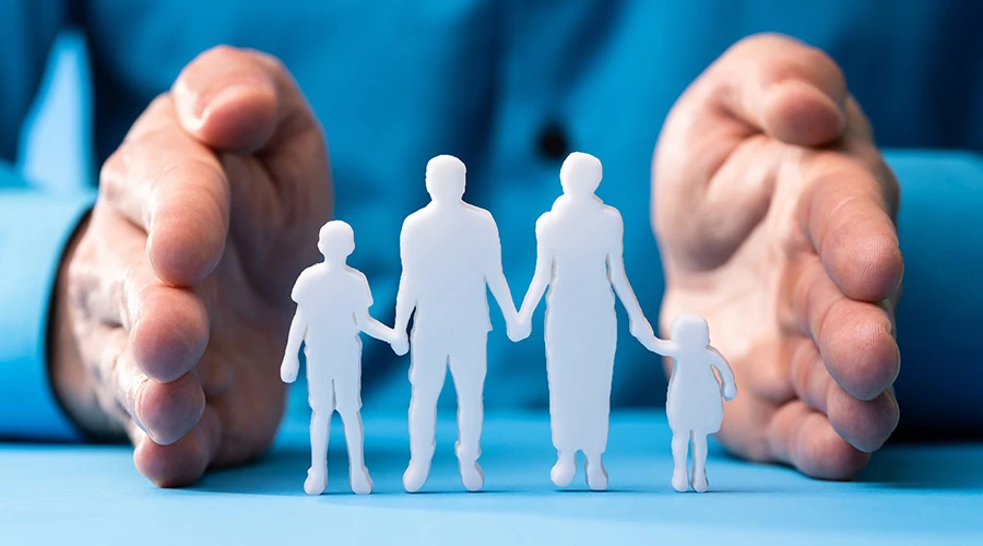 händer håller om pappfigurer på en familj